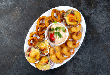 PERUVIAN FOOD. Piqueo caliente. Hot seafood platter fried shrimps, squid rings and baked scallops with sauce