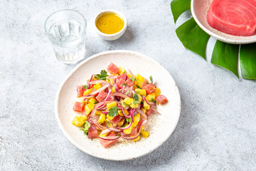 Tropical Hawaiian tahitian tuna mango salad on white plate on tropical monstera leafe