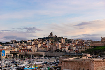 Fototapeta na wymiar Marseille, France - January 25, 2020: the view of the Basilica Notre-Dame de la Garde and the old port at sunset