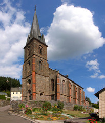Neo-gothic church with its high spire in Büdlich village, Hunsrück region in Germany