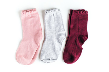 isolated pink, gray and burgundy baby socks on a white background