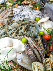 Closeup image of big assortment of fresh tasty uncooked seafood and vegetables on the market
