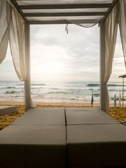Fototapeta na wymiar Toned image of sunbed under canopy at luxurious beach resort at ocean