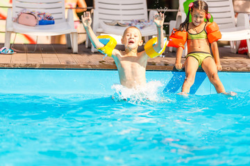 Smiling boy and little girl swimming in pool in aquapark