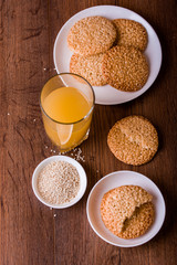 Round sesame cookies with milk and juice on the table.