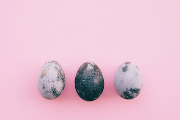 Natural dyed grey and white colored eggs on pastel pink background.