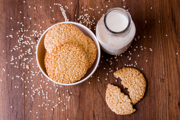 Round sesame cookies with milk and juice on the table.