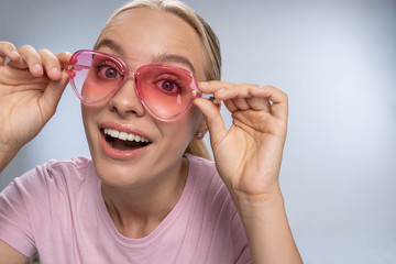 Cheerful blonde girl demonstrating her pink glasses