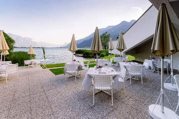 Luxury street restaurant with white tablecloth and flowers at Caldaro Lake in Italy