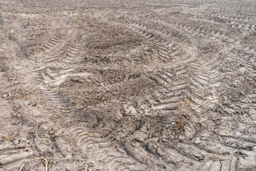 Fototapeta na wymiar Frozen ground soil with tractor tyre marks on a winter day