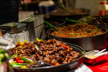 Street food, barbecuing on a hot grill with fire and smoke, thai food, vegetables and meat cooked for taking out. Brick Lane Food Market