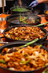 Street food, barbecuing on a hot grill with fire and smoke, thai food, vegetables and meat cooked for taking out. Brick Lane Food Market