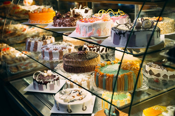 Pastry shop glass display with selection of cream or fruit cake.