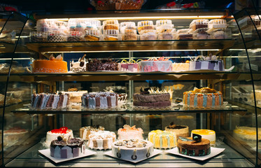 Pastry shop glass display with selection of cream or fruit cake.