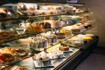 Pastry shop glass display with selection of cream or fruit cake.