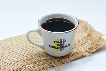 Traditional cup of Colombian coffee with coffee beans on wooden background