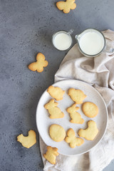 Easter cookies on a ceramic plate with napkin, grey stone background. Homemade butter and sugar cookies.