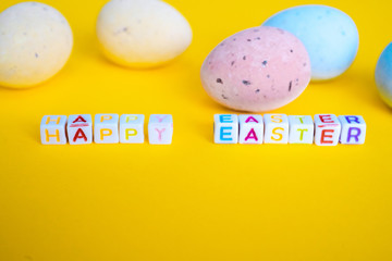 Easter greeting card with painted eggs. Seasonal Easter message  "Happy easter". Pastel and colorful   decorated easter eggs with greeting card with text on yellow background. Spring holidays concept.