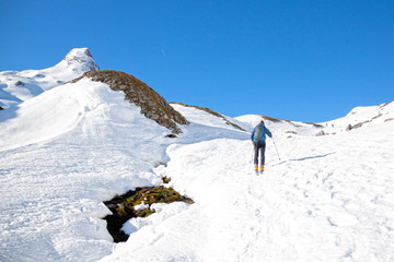 man in a valley surrounded of mountains in a sunny day covered of snow