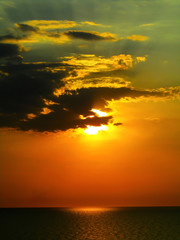 Fototapeta premium The sun hid behind the clouds at sunset over the sea
