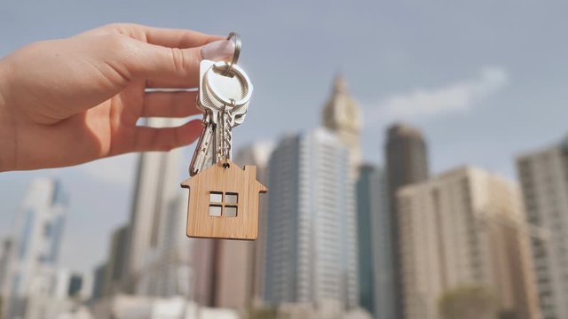 The concept of buying an apartment in Dubai skyscrapers. The girl holds in her hand the keys to a new apartment.