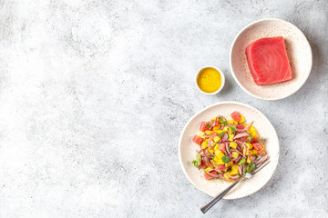 Gourmet tuna mango salad tartar with cilantro and purple onion on white plate