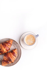 Croissants and a cup of coffee on a white wooden table. Morning still life. Top view with space for text. Flat lay composition. Background for restaurant, bakery, cafe.