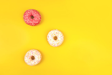 Pink and white donuts on yellow backdrop with copyspace.