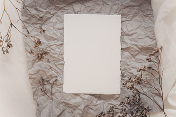 Wedding invitation mockup with dry plants , papers on white textile background. Top view, flat lay....