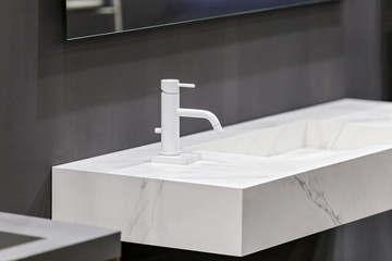 Marble white sink on the background of gray concrete wall, white mixer sink tap