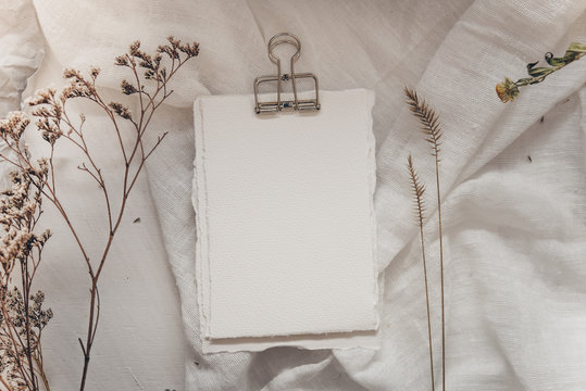 Wedding invitation mockup with dry plants , papers on white textile background. Top view, flat lay. Wedding stationary. Perfect for presentation of your invitation, menu, greeting cards