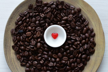  Processed coffee beans and tostao, with red heart on wooden background