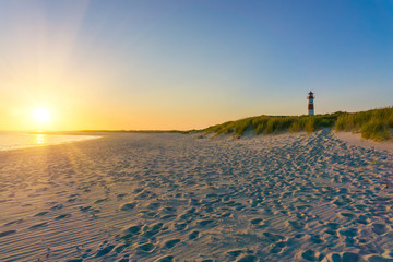 Germanys North Sea Coast. Long empty beach with a Lighthouse at sunrise.