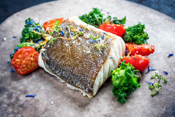 Gourmet gebratenes Skrei Kabeljau Fisch Filet mit Kalette und Tomaten als closeup auf einem Modern Design Teller