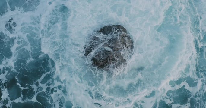Aerial view of powerful waves breaking over a rocky coastline at dusk, moody nature backgrounds