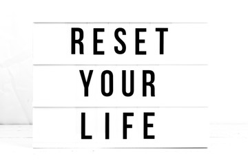 Reset Your Life flat lay on a wooden white background.  Motivational business start up board. Retro