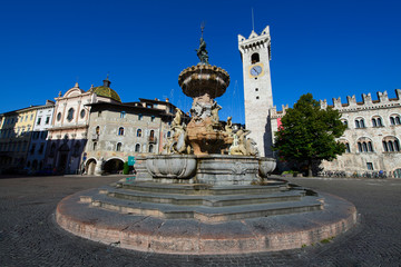Fontana con scalini e statue che fuoriesce acqua del centro città di Trento, con sfondo delle case...