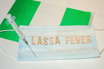 Nigerian flag under words Lassa fever outbreak concept. protective breathing mask and syringe....