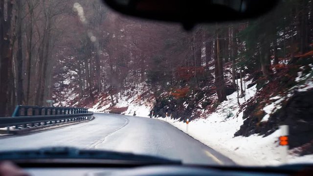 man rides behind the wheel of a car on a mountain serpentine in winter