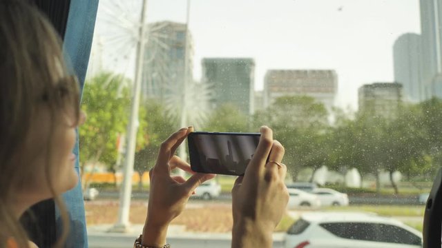 A girl travels by bus through the city of Abu Dhabi and makes video on the phone. UAE.