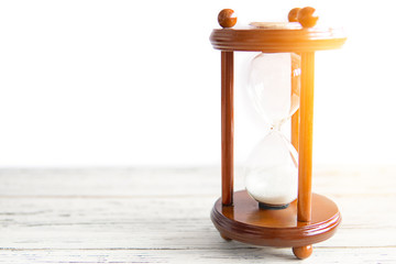 Vintage wooden hourglass sandglass retro clock on white wooden background. Copy space. Countdown, deadline concept. Sun light effect