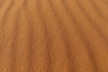 Fototapeta na wymiar sand texture - background of desert sand dunes. Beautiful structures of sandy dunes. sand with wave from wind in desert - Close up