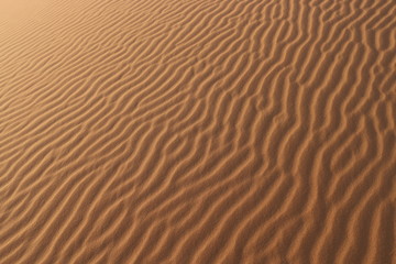 sand texture - background of desert sand dunes. Beautiful structures of sandy dunes. sand with wave from wind in desert - Close up