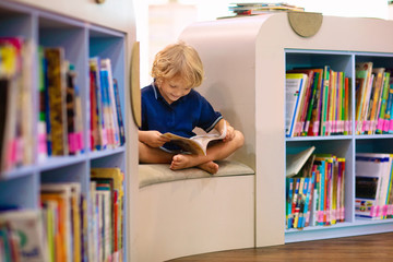 Child in school library. Kids reading books.