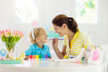 Mother and kids, family coloring Easter eggs.