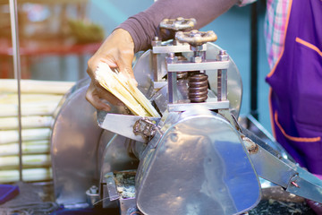 man squeezes a sugar cane to make fresh, organic juice with a hand powered juicer. Healthy product.