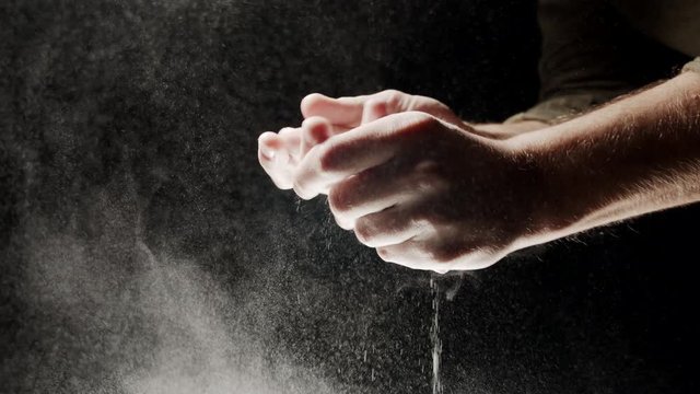Fitness athlete clapping hands with chalk powder in slow motion 