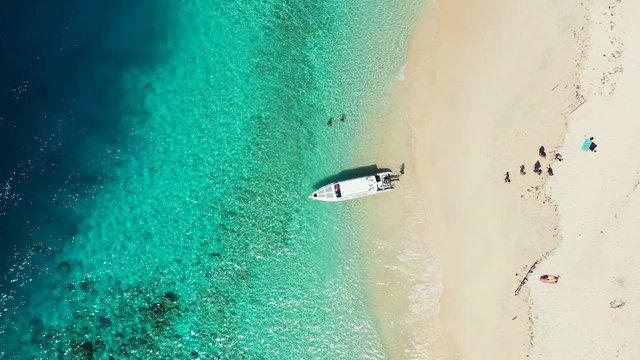 Small water taxi boat floating on the crystal clear turquoise sea water near sandy beach. Antigua