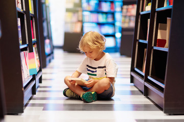 Child in school library. Kids reading books.