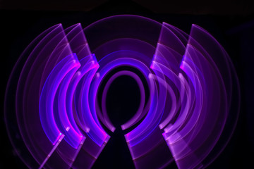 Curved abstract shape made with a light saber violet. Lightpainting session at night. Leds light effect. Background for wallpaper.
